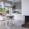 Real photo of a dining table, chairs and kitchen interior. Storage for fireplace wood. Empty wall, place for your poster